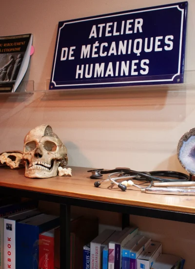 Photographie dans le cabinet de Benoit Huard avec un crâne humain et une plaque avec inscrit "atelier de mécaniques humaines"